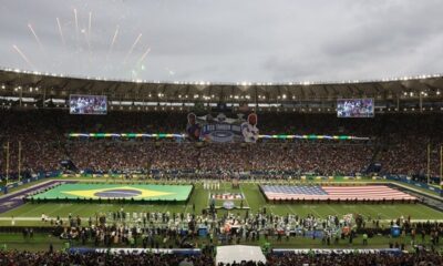 Estádio Maracanã lotado, bandeiras do Brasil e EUA no campo de futebol, fogos de artifício