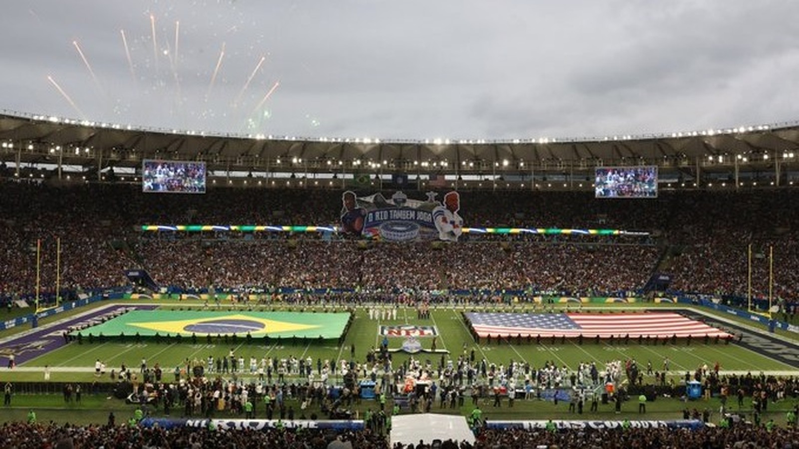 Estádio Maracanã lotado, bandeiras do Brasil e EUA no campo de futebol, fogos de artifício
