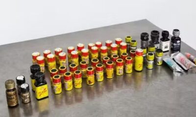 Dezenas de frascos pequenos amarelos, pretos e dourados sobre superfície metálica