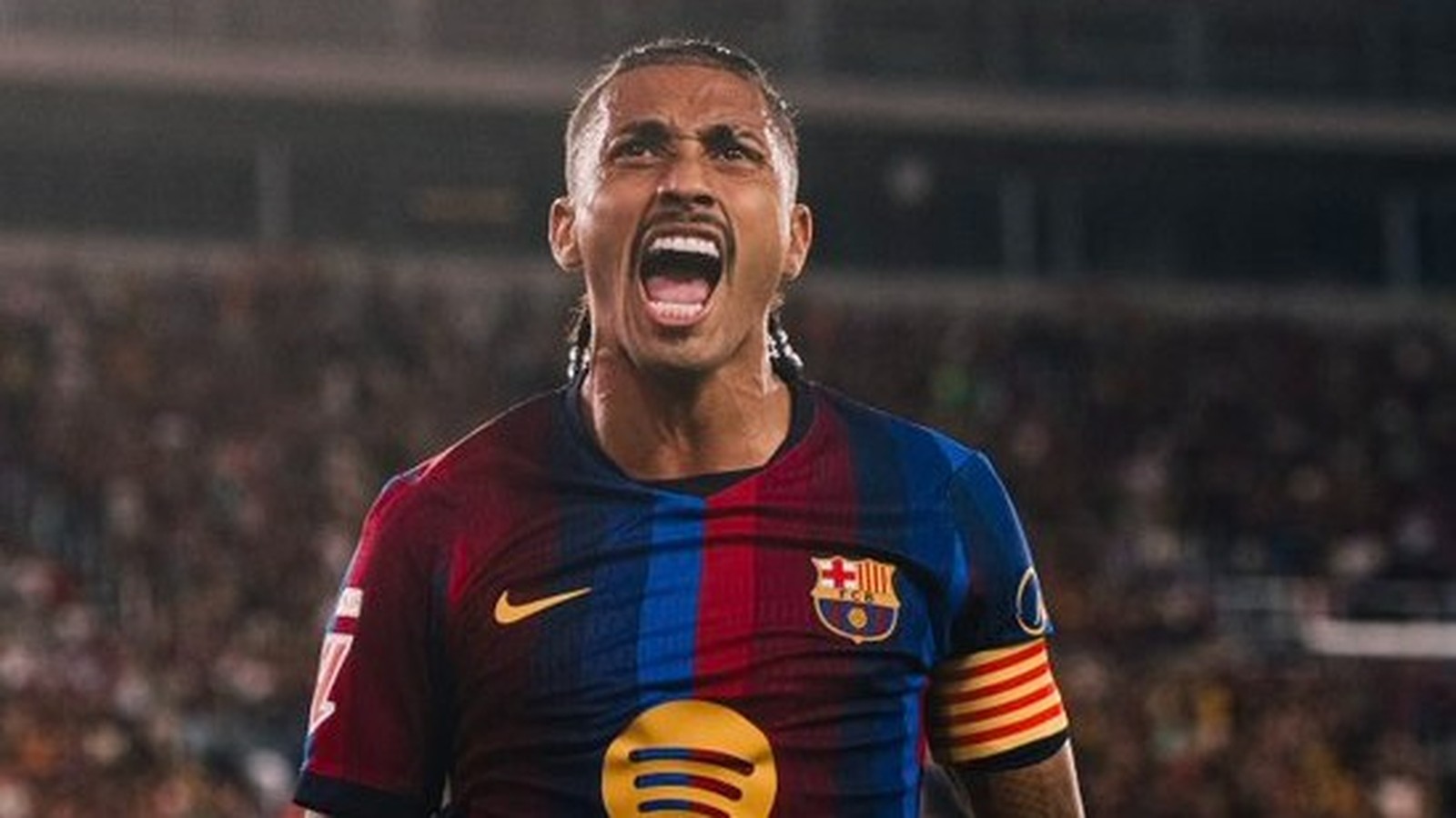 Raphinha do Barcelona celebra vestindo camisa azul e vermelha listrada em campo