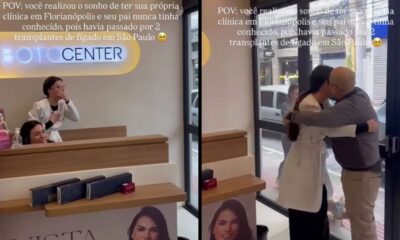 Mulher surpreendida pelo pai em sua clínica, emocionados abraçam-se ao lado de letreiro BOTO CENTER