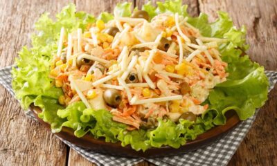 Salpicão de frango com batata palha, milho, azeitonas, uva passa, cenoura e alface em uma travessa