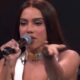 Anitta segura microfone, gesticulando, em programa "AO VIVO" na TV