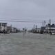 Rua com casas em Surf City, Nova Jersey, completamente inundada sob céu cinzento