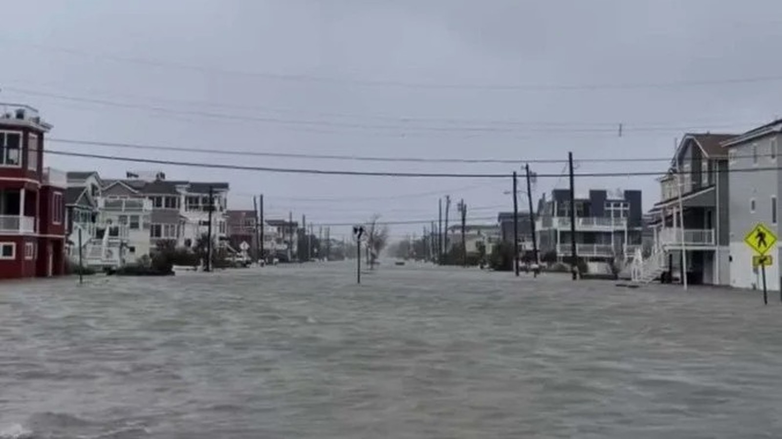 Rua com casas em Surf City, Nova Jersey, completamente inundada sob céu cinzento