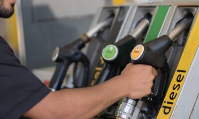 Mão segura bico de bomba de combustível 'B7 diesel' em posto, com 'diesel' visível