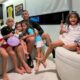 MC Poze do Rodo e seis crianças sorrindo em um sofá com lollipops e balão