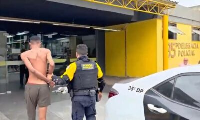 Policial da Força Municipal conduz homem algemado para delegacia com placa '35ª Delegacia Policial'