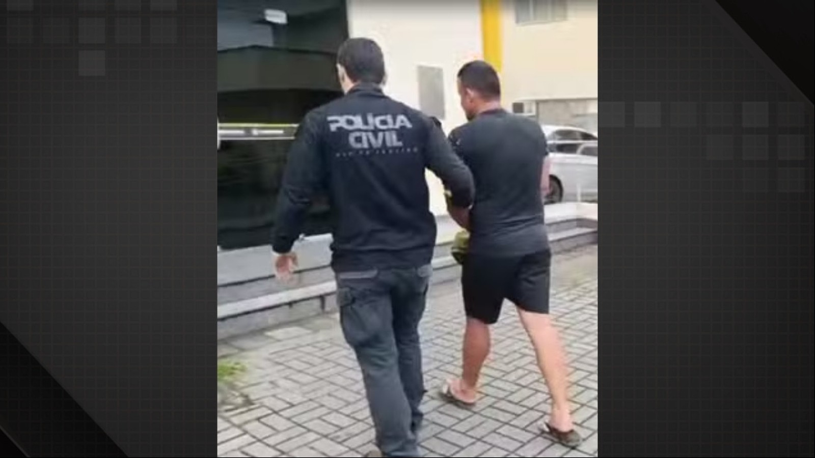 Agente da Polícia Civil escolta homem algemado, vestindo camiseta e shorts escuros