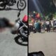 Cena dividida: pessoa borrada no chão ao lado de moto e aglomeração noturna de pessoas e motos na rua