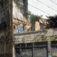 Fachada de prédio antigo com lado direito desabado, teto destruído e vegetação abundante