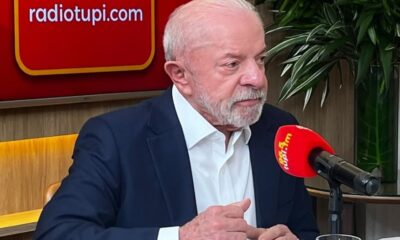 Luiz Inácio Lula da Silva em estúdio de rádio com microfone e painel 'radiotupi.com'