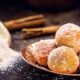Bolinhos de chuva em prato de cobre, cobertos com açúcar e canela, sobre bancada de madeira