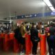 Muitas pessoas em catracas de estação com sinais indicando 'Rock in Rio' e 'BRT'