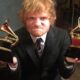 Ed Sheeran, ruivo e barbudo, em terno, segura dois troféus Grammy dourados