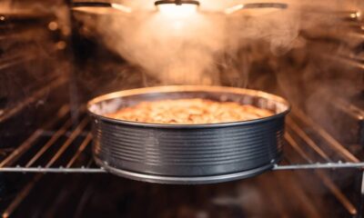 Bolo dourado em forma redonda assando em forno com vapor e luz acesa