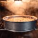 Bolo dourado em forma redonda assando em forno com vapor e luz acesa