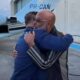 Dois homens abraçando em frente a uma aeronave azul com a inscrição PR-CAN na cauda