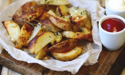 Batatas em gomos assadas com temperos, sal grosso, e dois molhos em potes brancos