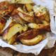 Batatas em gomos assadas com temperos, sal grosso, e dois molhos em potes brancos