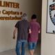Dois homens em corredor da Polícia Civil. Placas 'DC-POLINTER' e 'BASE URANO' ao fundo