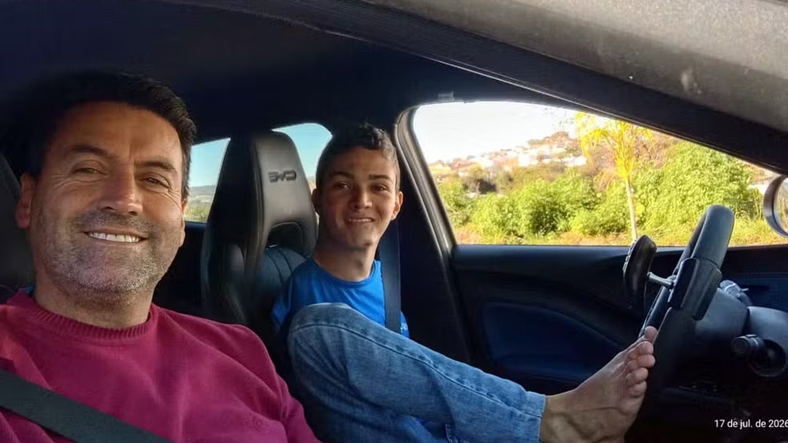 Jovem com pé no volante de carro. Homem ao lado. CAE, 17 de jul. de 2026