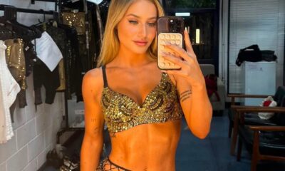 Bruna Griphao em selfie de espelho, vestindo top dourado de paetês, segurando celular, em bastidores