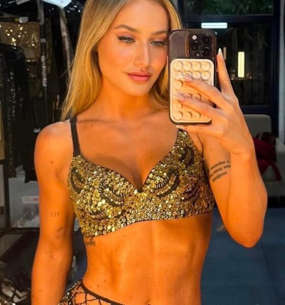Bruna Griphao em selfie de espelho, vestindo top dourado de paetês, segurando celular, em bastidores