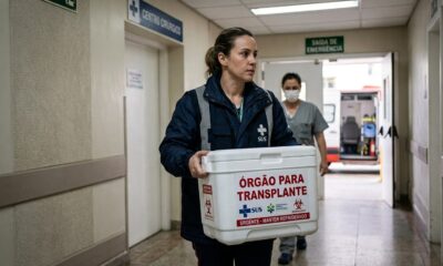 Profissional de saúde carrega caixa ‘ÓRGÃO PARA TRANSPLANTE’ em corredor de hospital com ambulância