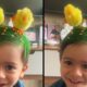 Menino sorrindo com cabelo verde decorado com milho e dois pintinhos de brinquedo na cabeça