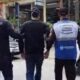Três homens de costas: um policial civil, um preso e um agente de segurança pública