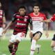 Jogador do Flamengo dribla a bola em jogo contra dois atletas do Estudiantes