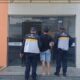 Dois guardas ROMU escoltam homem para Delegacia Civil com letreiro "Mulher" e logo
