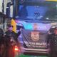 Três policiais fardados com armas e bandeira PMERJ em frente a um caminhão Scania R150