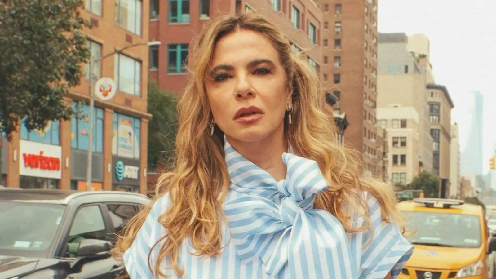 Close-up de Luciana Gimenez com camisa listrada azul e branca em rua urbana