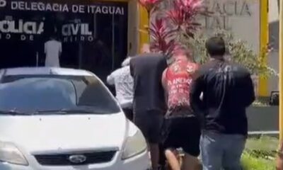 Homens escoltados chegam à Delegacia de Itaguaí, Polícia Civil, com carro branco na frente