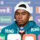 Jovem jogador Endrick em coletiva de imprensa, usando boné branco e moletom teal com logos de patrocinadores