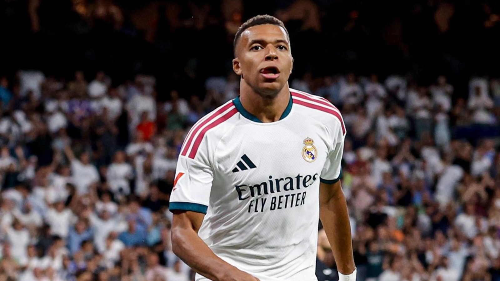 Kylian Mbappé com camisa branca do Real Madrid e logos "Emirates FLY BETTER" e Adidas