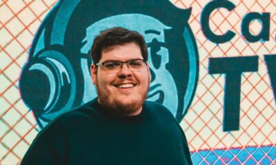 Casimiro Miguel sorrindo com óculos e barba, em frente ao logo da CazéTV