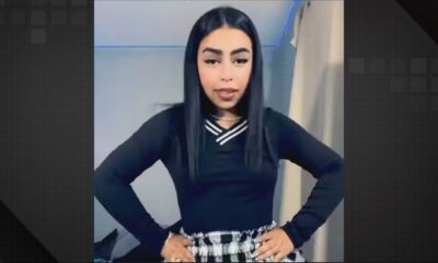 Retrato de mulher jovem com cabelo preto liso, camisa preta com detalhes brancos e saia xadrez