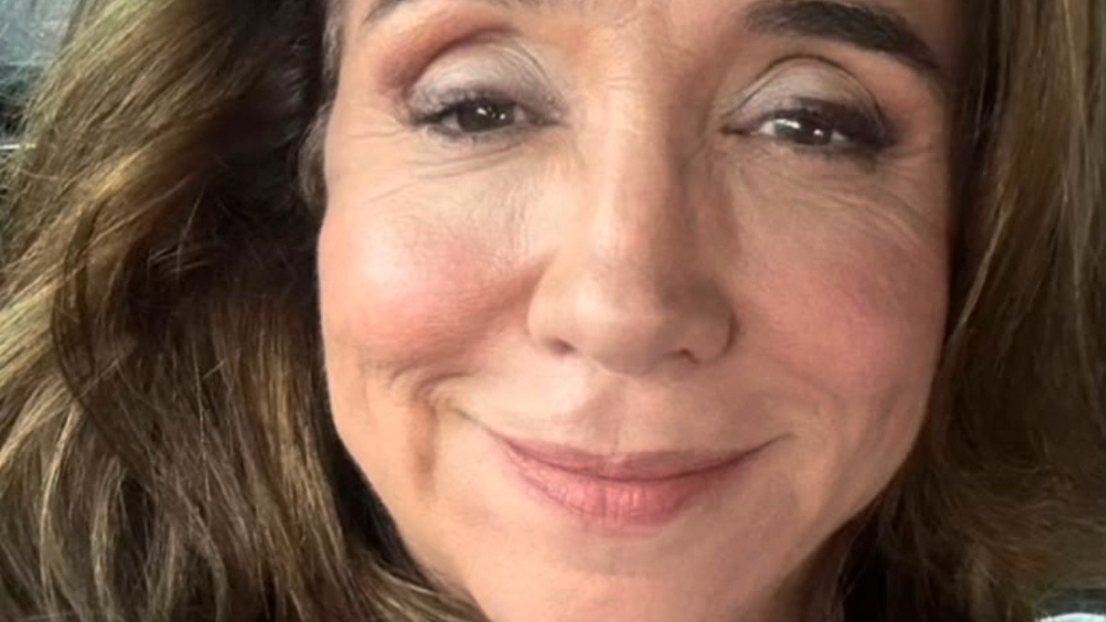 Rosto da atriz Marisa Orth sorrindo levemente, com covinhas e cabelo castanho ondulado