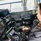 Eliana Moreno no cockpit de helicóptero, com fones de ouvido e operando controles