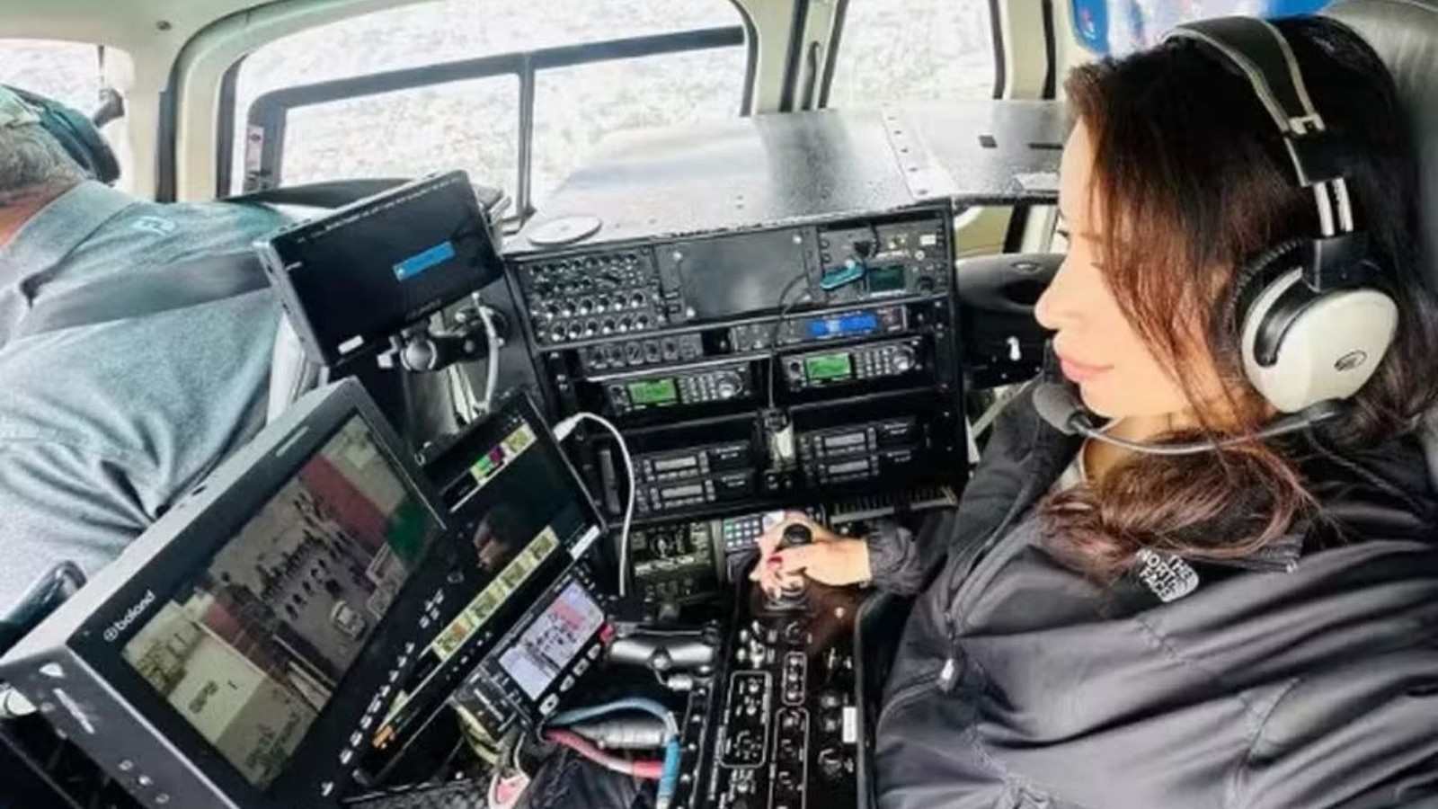 Eliana Moreno no cockpit de helicóptero, com fones de ouvido e operando controles