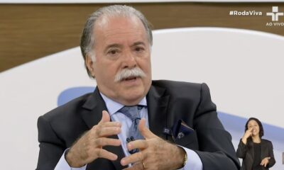 Tony Ramos em terno e gravata, gesticulando. Intérprete Libras e texto #RodaViva AO VIVO