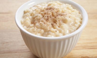 Arroz doce em tigela branca com canela em pó sobre uma superfície de madeira