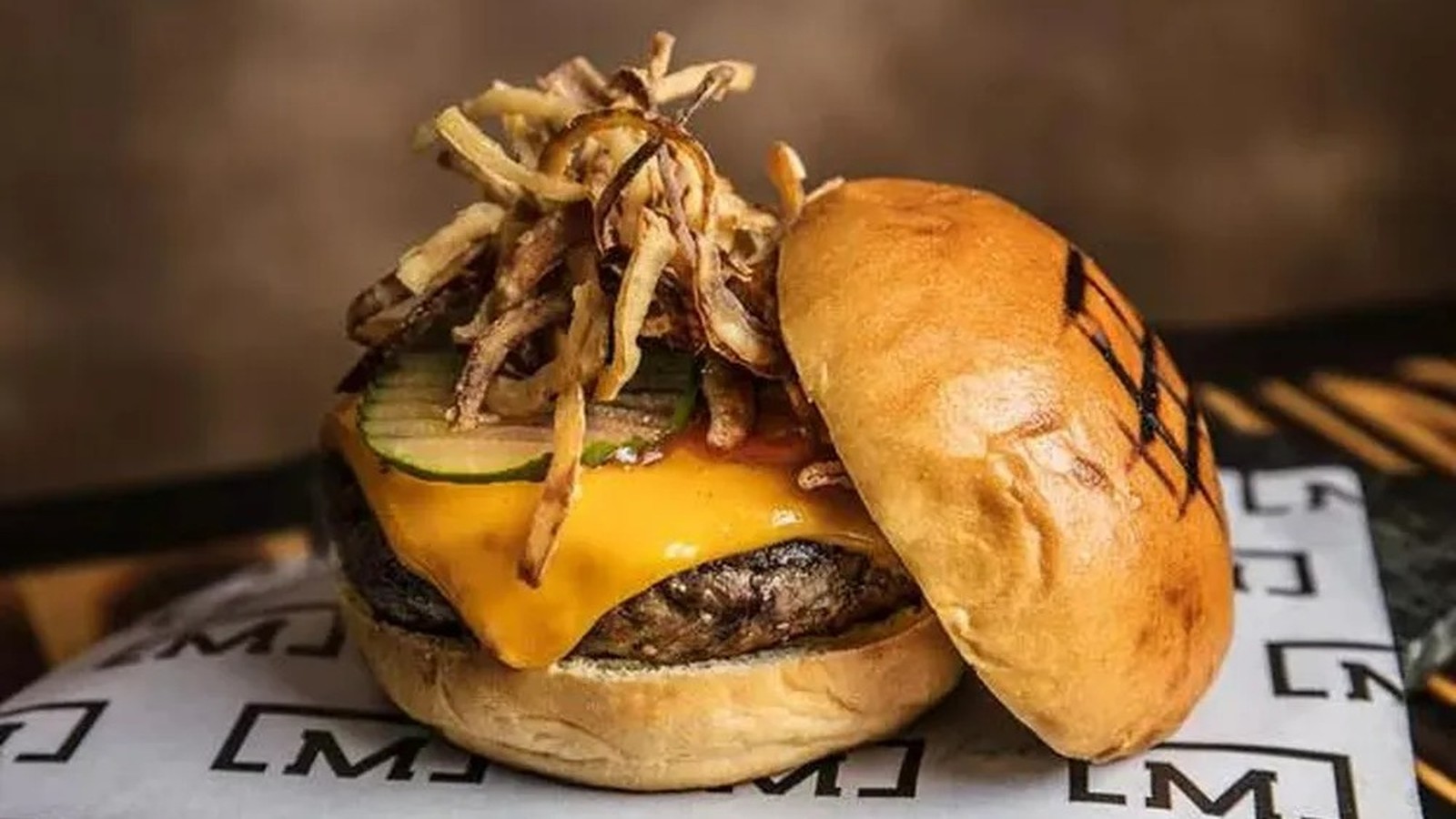 Hambúrguer gourmet com carne, queijo derretido, picles, cebola crocante e pão tostado