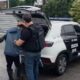 Dois policiais prendem um homem ao lado de viatura da Polícia Civil, com inscrições 24ª DP