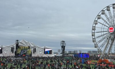 Festival ao ar livre com multidão, palco, roda-gigante Itaú e céu nublado
