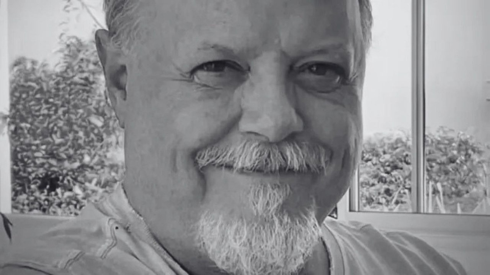 Retrato em preto e branco de Roney Facchini sorrindo com bigode e cavanhaque