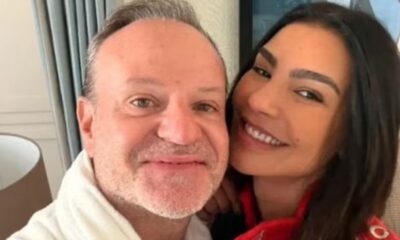Close-up de Rubens Barrichello e Cíntia Chagas sorrindo para a câmera, abraçados